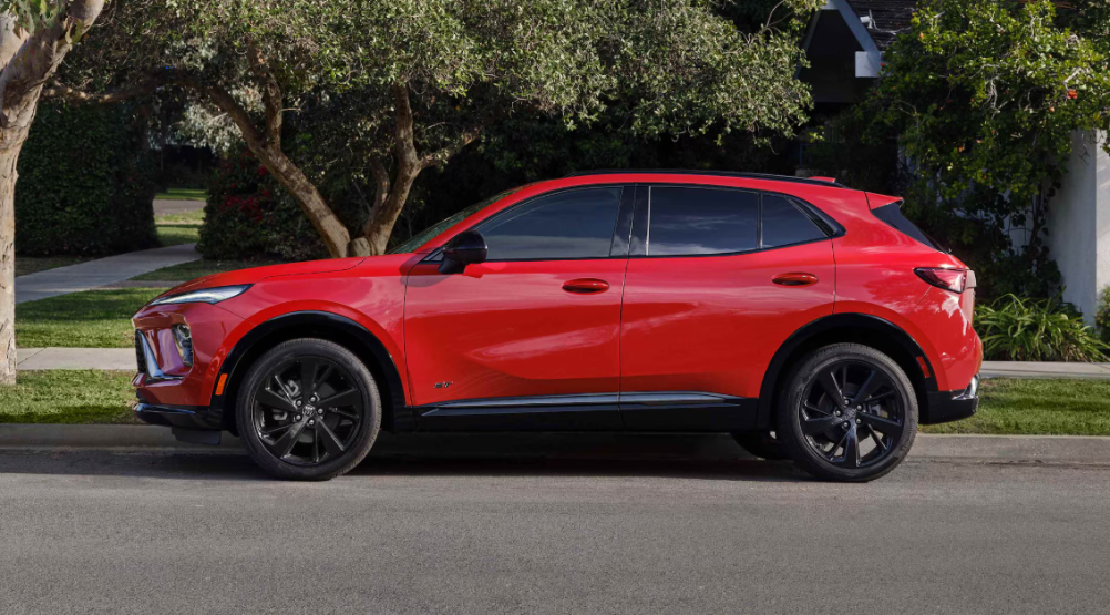 A red Buick Envision in profile, parked by the curb in a suburb.