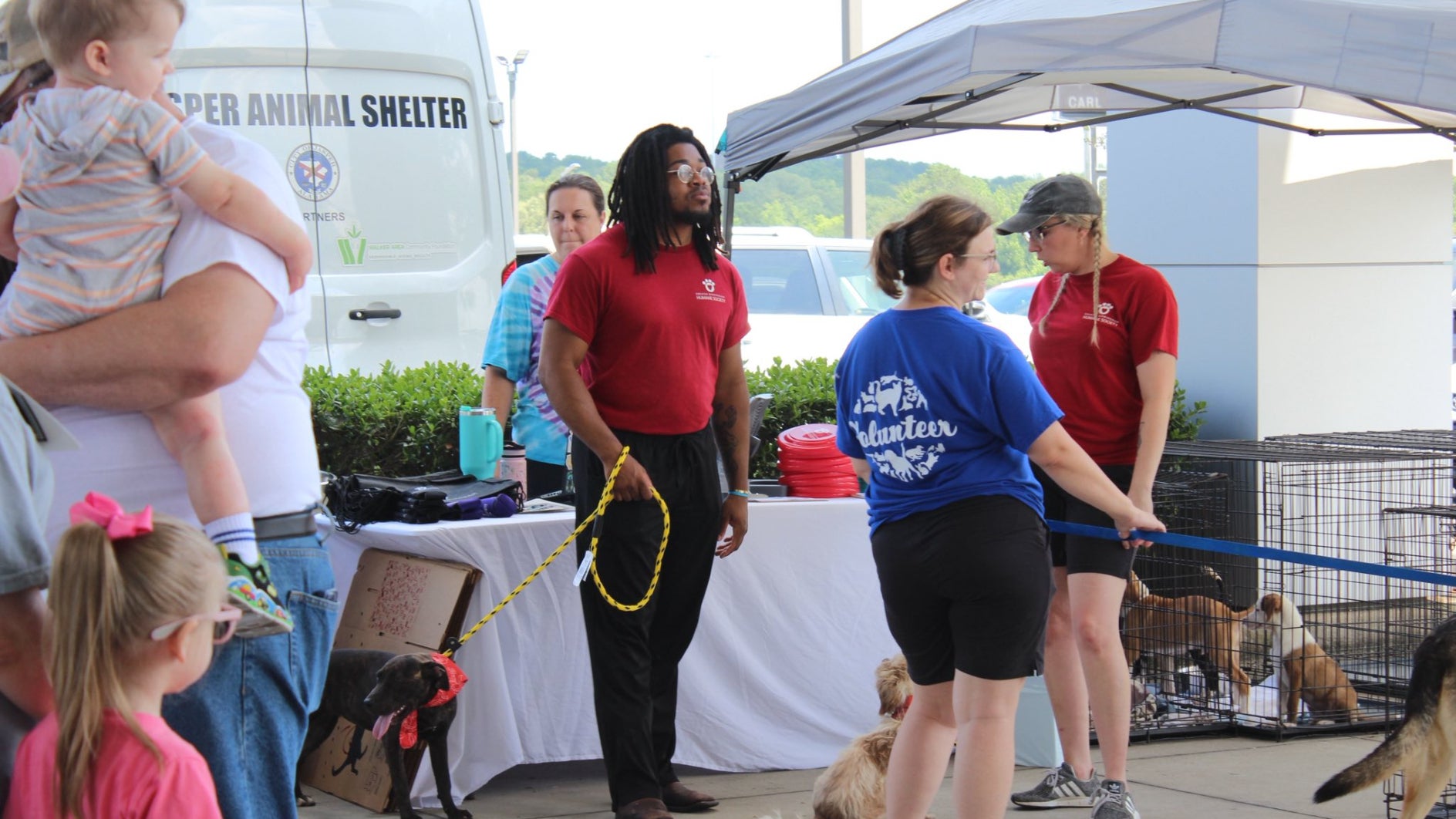 The Ruff Rescue event with Carl Cannon employees holding onto dog leashes as customers walk by.