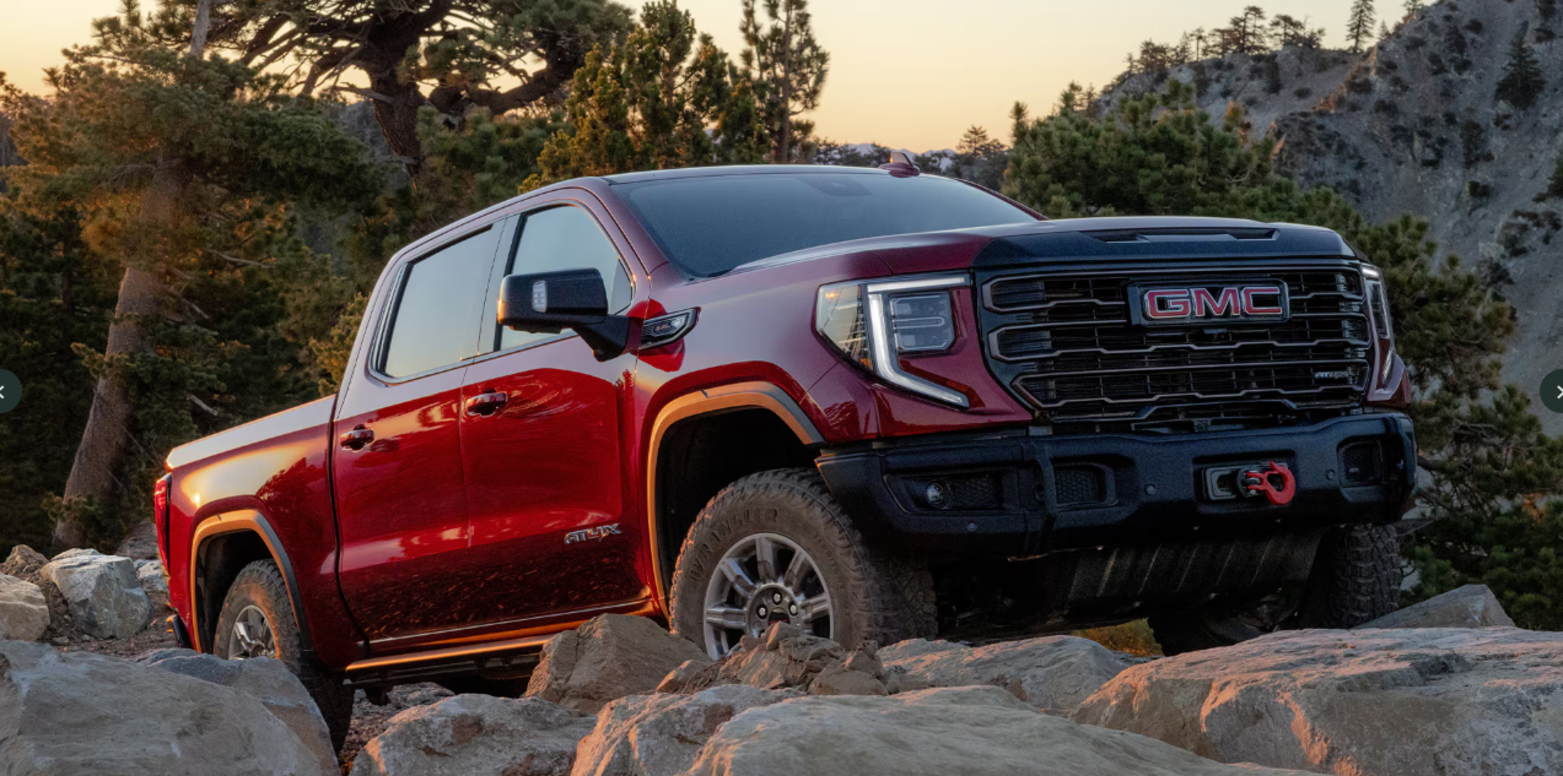 A red GMC Sierra 1500 driving over rocks.