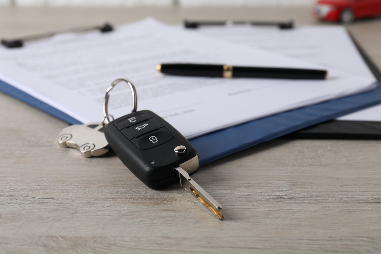 A car key fob resting beside a vehicle financing contract.