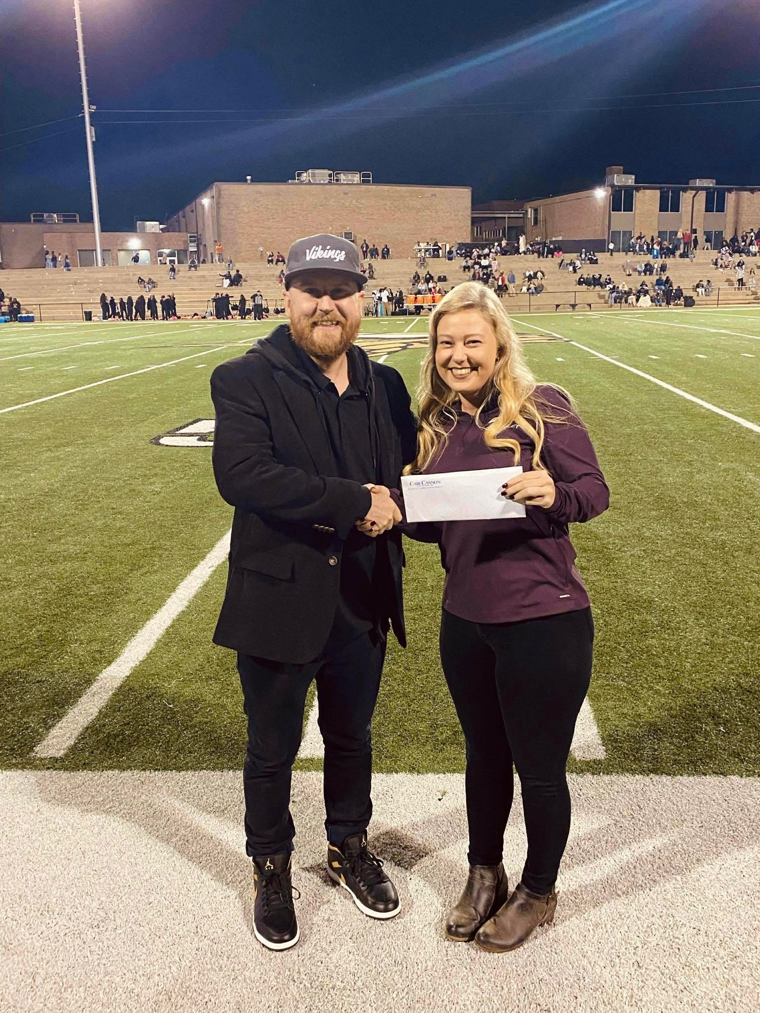Sales Consultant Allison Goforth and United States Marine Corp veteran Jonathan Timmons in front of a football field